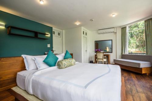 a bedroom with a large white bed with blue pillows at Viyana Boutique Hotel in Kandy