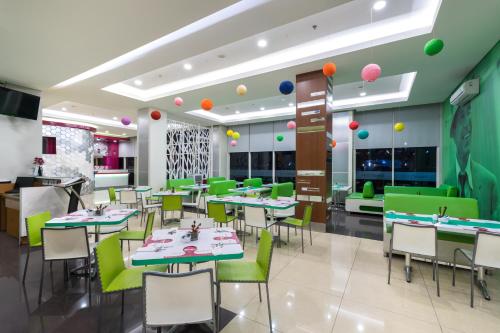 a restaurant with green tables and chairs and balloons at favehotel Padjajaran Bogor in Bogor