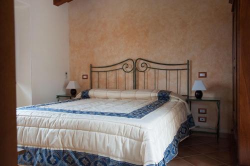 Palizzi的住宿－阿古尼阿格利圖里斯莫艾露坎達酒店，一间卧室配有一张大床和两盏灯。