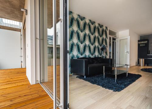 a living room with a black couch and a glass table at In Apartments in Brno