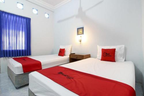 a room with two beds with red and white sheets at RedDoorz Syariah At Jalan Menteri Supeno in Yogyakarta