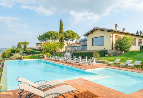 a swimming pool with chairs and a house at Borgo Divino in Montespertoli