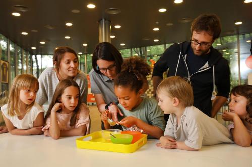 a group of children sitting at a table playing with a toy at Hotel Món Sant Benet in Sant Fruitos de Bages
