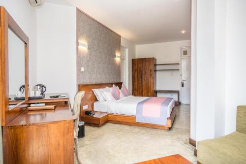 a bedroom with a bed and a desk and a kitchen at Viyana Boutique Hotel in Kandy