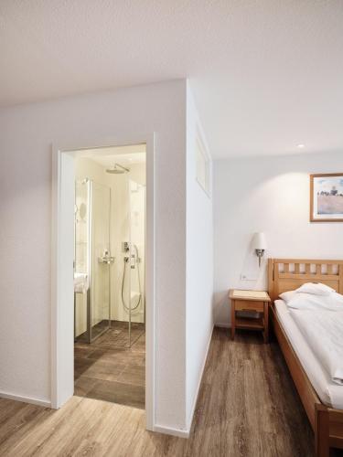 a bedroom with a bed and a shower at Badhotel Restaurant Stauferland in Bad Boll