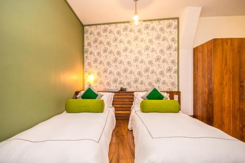 two beds in a small room with green cushions at Viyana Boutique Hotel in Kandy
