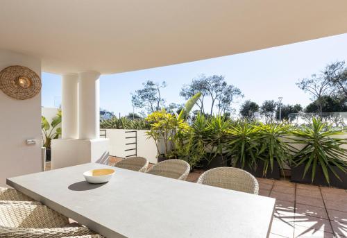 a white table and chairs on a patio with plants at Bay Royal Apartments in Byron Bay