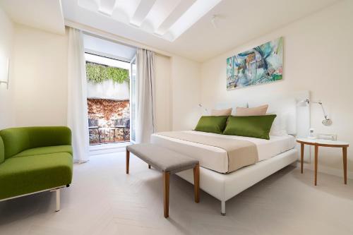 a white bedroom with a bed and a green chair at Hotel Villa Blu Capri in Anacapri