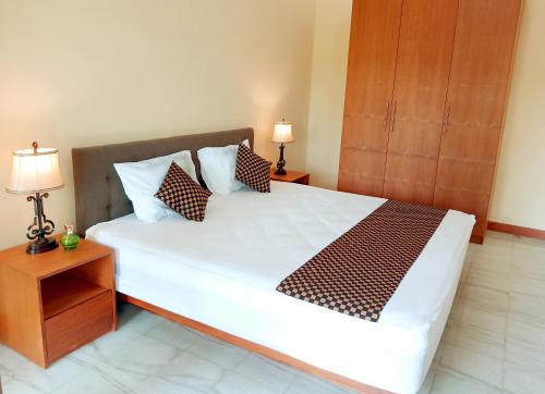 a bedroom with a large white bed with two lamps at The Terrace House in Denpasar