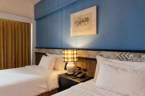a hotel room with two beds and a blue wall at Witz Bangkok Ramkhamhaeng in Bangkok