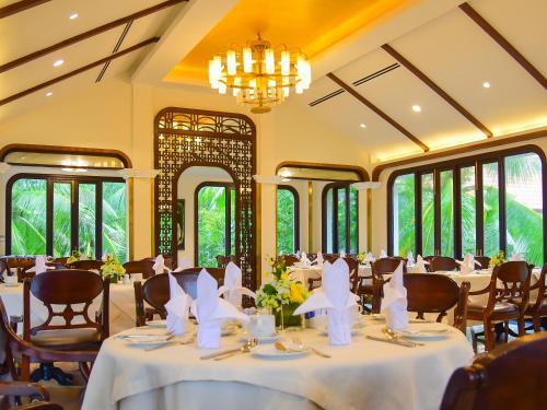 a dining room with tables and chairs and windows at Furama Villas Danang in Da Nang