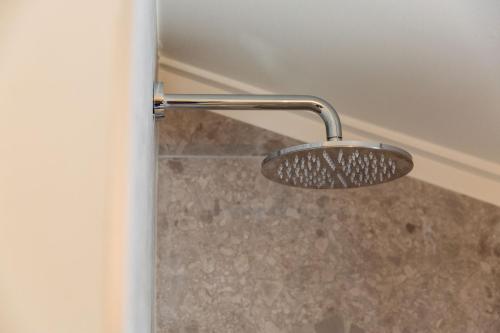 a shower head in a bathroom with a marble floor at C-Hotels Zeegalm in Middelkerke