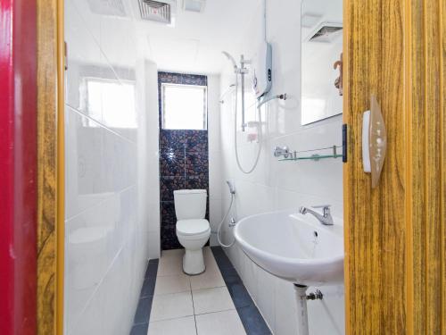 ein weißes Bad mit einem WC und einem Waschbecken in der Unterkunft Super OYO 414 Adiff Palace Hotel in Sepang