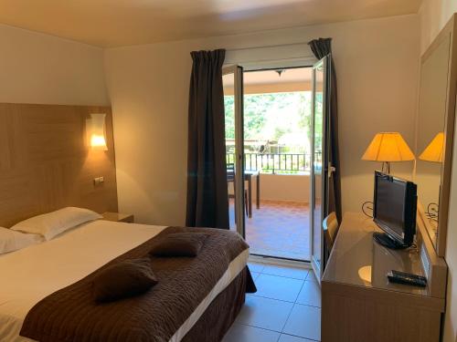 Schlafzimmer mit einem Bett, einem TV und einem Balkon in der Unterkunft Domaine de l'Oriu in Serriera