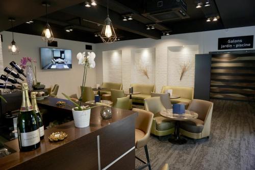 a restaurant with a bar with chairs and wine bottles at Golden Tulip Roissy Saint Witz in Saint-Witz