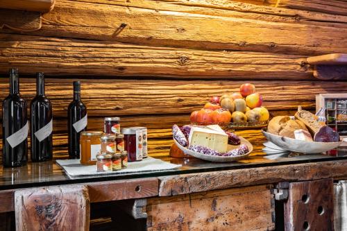 Chambres d'hôtes La Moraine Enchantée في أَويستا: طاولة مع زجاجات من النبيذ والفواكه والخبز