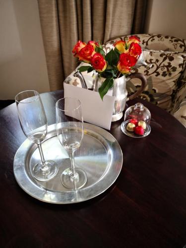 a wooden table with two glasses and a tray with roses at Meerendal Boutique Hotel in Durbanville