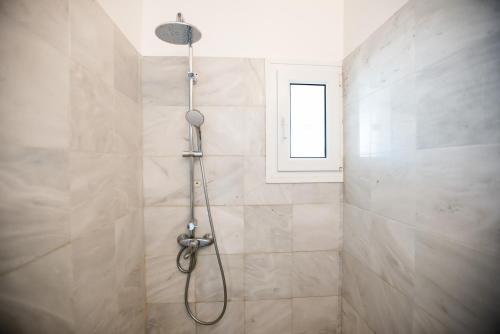 a shower with a hose in a bathroom with a window at Bleland Mykonos II in Ano Mera