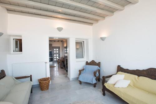 a living room with white walls and a couch and chairs at Bleland Mykonos II in Ano Mera