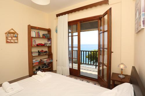 a bedroom with a bed and a balcony with the ocean at Seaside in Agia Paraskevi