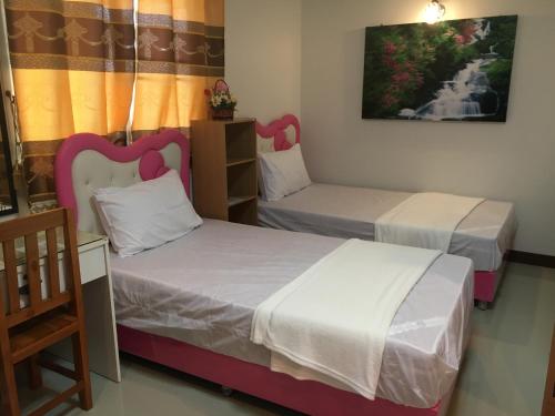 a room with two beds and a chair at บุญจินดา รีสอร์ท in Ban Phayom