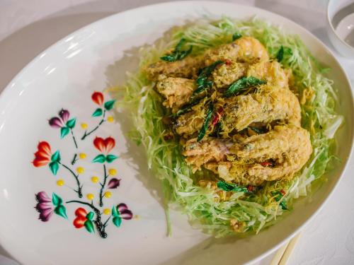 a plate of food with chicken on lettuce at Banyu Biru Villa in Lagoi