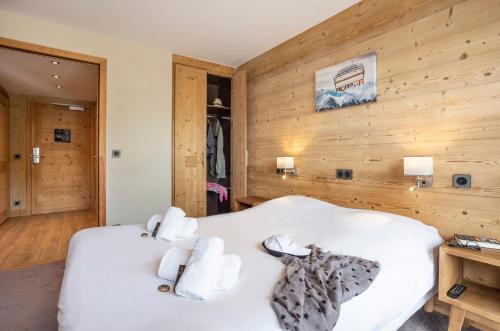 a bedroom with a white bed with wooden walls at Résidence Daria-I Nor by les Etincelles in L'Alpe-d'Huez