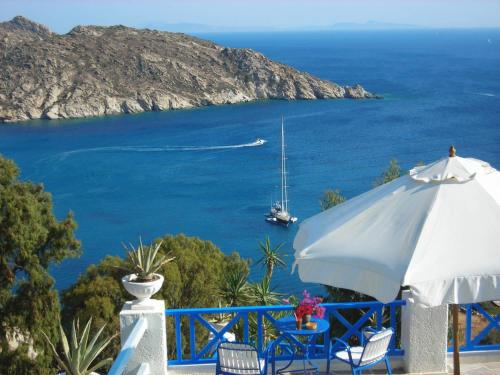 a white umbrella and chairs and a boat in the water at Ios Pelagos in Ios Chora