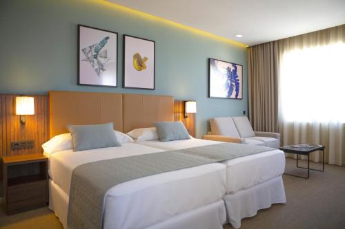 a hotel room with a large bed and a chair at Riu Plaza España in Madrid
