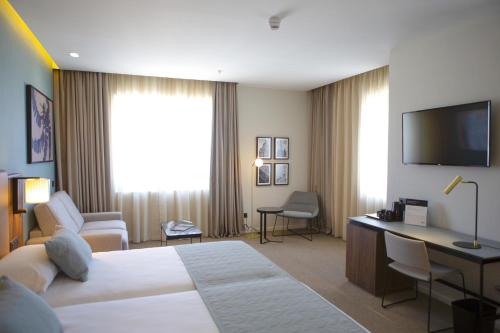 a hotel room with a bed and a desk and a television at Riu Plaza España in Madrid