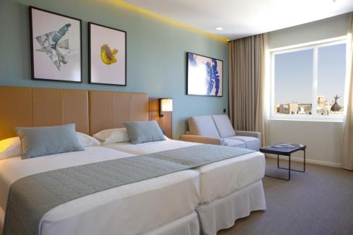 a hotel room with a large bed and a chair at Riu Plaza España in Madrid