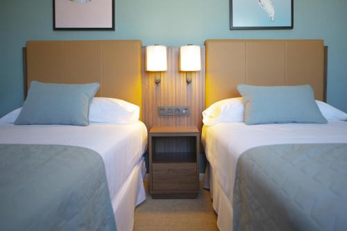 a hotel room with two beds and a table between them at Riu Plaza España in Madrid