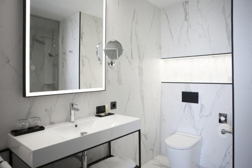a white bathroom with a sink and a toilet at Riu Plaza España in Madrid