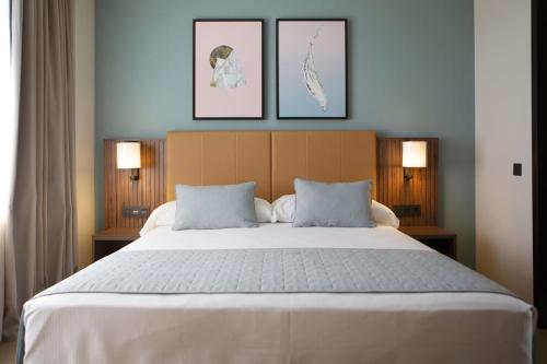 a bedroom with a large bed with three pictures on the wall at Riu Plaza España in Madrid