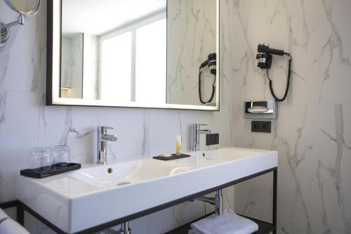 a white bathroom with a sink and a mirror at Riu Plaza España in Madrid