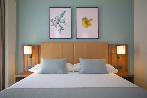 a bedroom with a large bed with three pictures on the wall at Riu Plaza España in Madrid