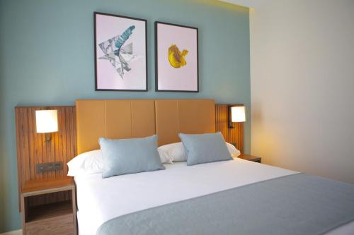 a bedroom with a large bed with three pictures on the wall at Riu Plaza España in Madrid