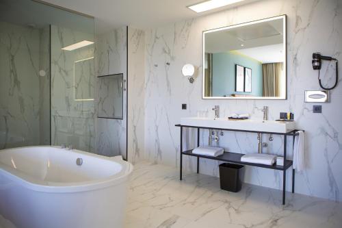 a bathroom with a tub and a sink and a mirror at Riu Plaza España in Madrid