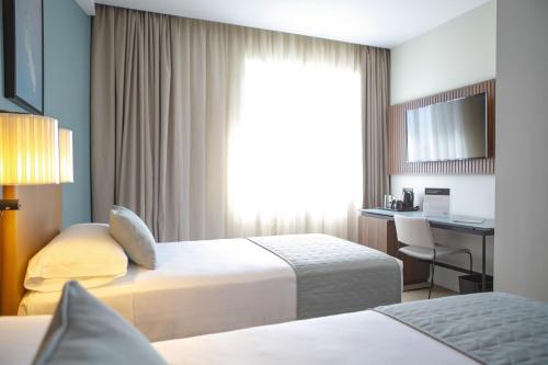 a hotel room with two beds and a desk at Riu Plaza España in Madrid