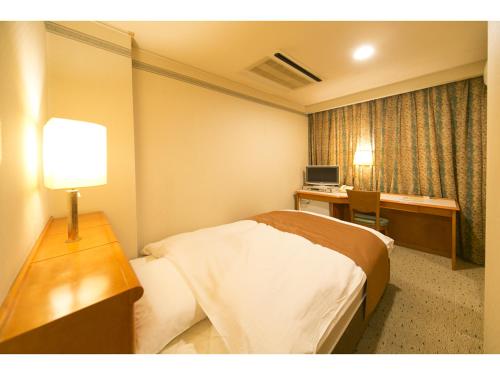 a hotel room with a bed and a desk at Hyper-inn Takamatsu Ekimae in Takamatsu