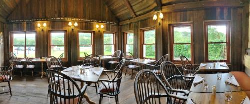 Un comedor con mesas y sillas y ventanas. en Rokeby Manor, en Invergarry