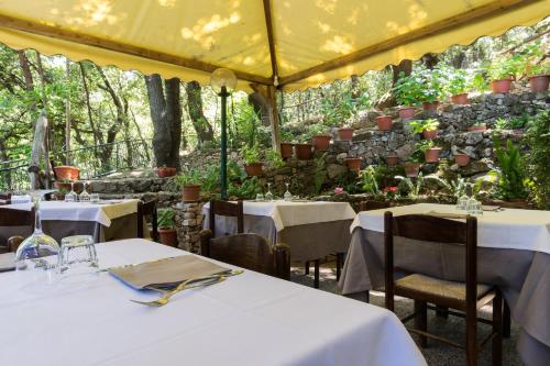 a restaurant with white tables and chairs and plants at S'Enis Monte Maccione in Oliena