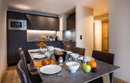 a kitchen with a table with plates and fruit on it at Résidence Daria-I Nor by les Etincelles in L'Alpe-d'Huez