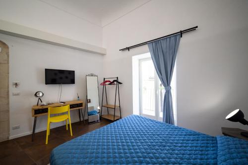 um quarto com uma cama azul, uma secretária e uma janela em A casa di Cassi em Modica