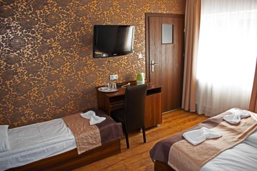 a hotel room with two beds and a desk and a television at Dom Bursztynowy in Jantar