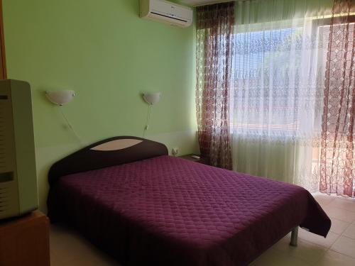 a bedroom with a purple bed in front of a window at apartament Sea Star in Byala