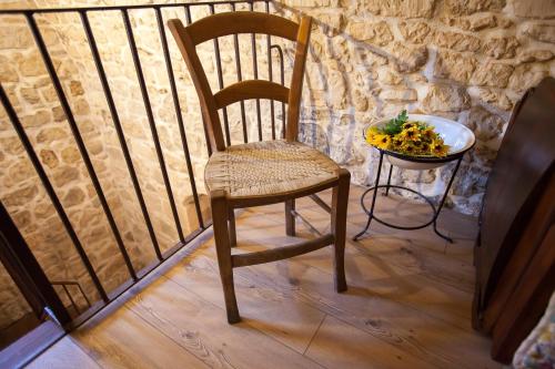 a wooden chair and a bowl of fruit on a balcony at Si-Moutique, le Case-grotte degli Avi 2 in Modica