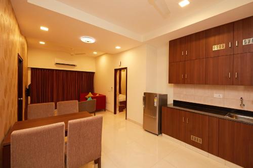 a room with a table and chairs and a kitchen at Hotel Kamar Residences and Banquets in Chennai