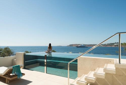 a woman is standing on a house with a swimming pool at Four Seasons Astir Palace Hotel Athens in Athens