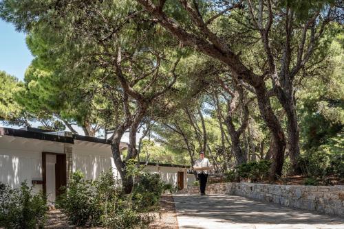 a woman walking down a sidewalk next to a tree at Four Seasons Astir Palace Hotel Athens in Athens